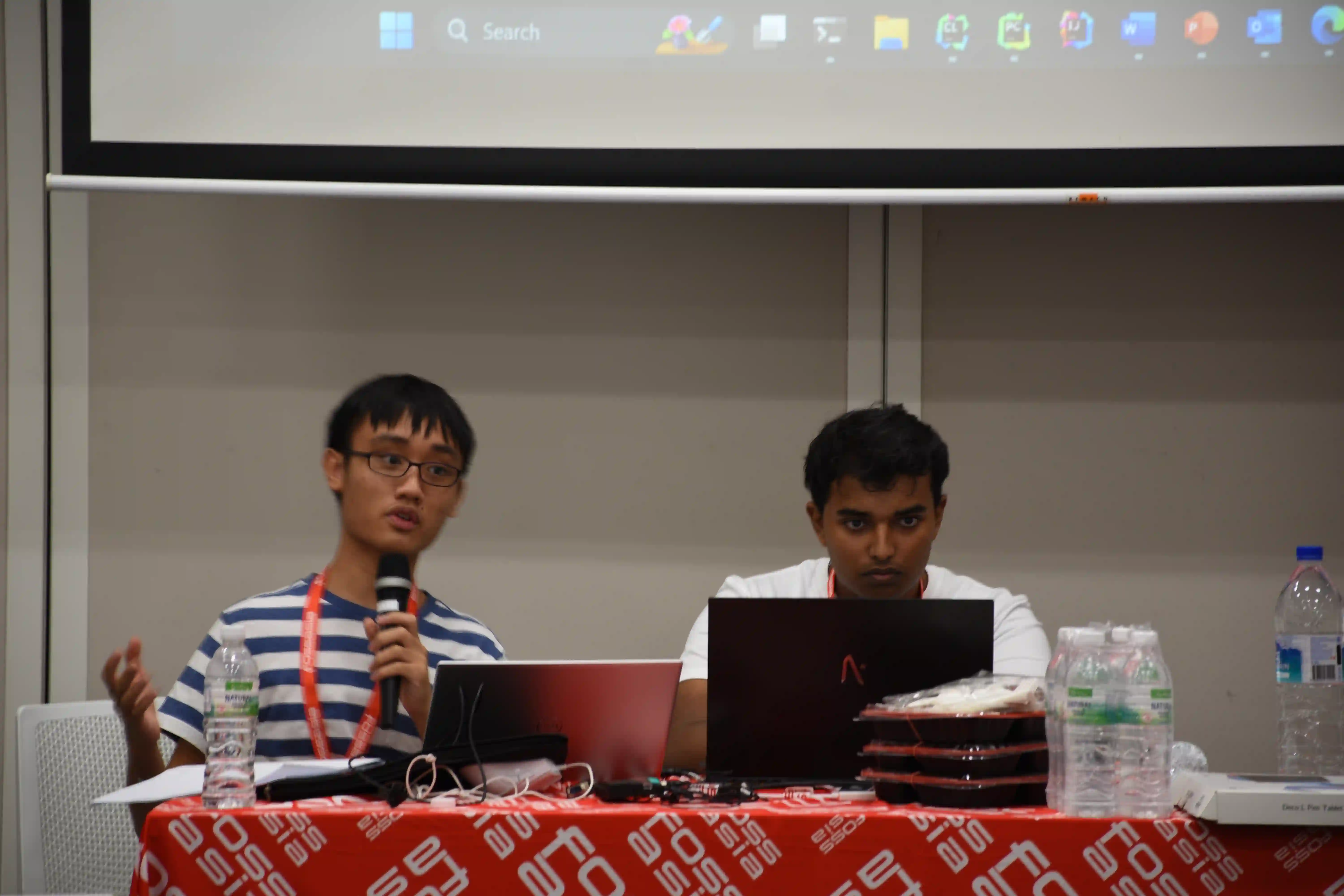 Two organisers speaking at a FOSSASIA event
